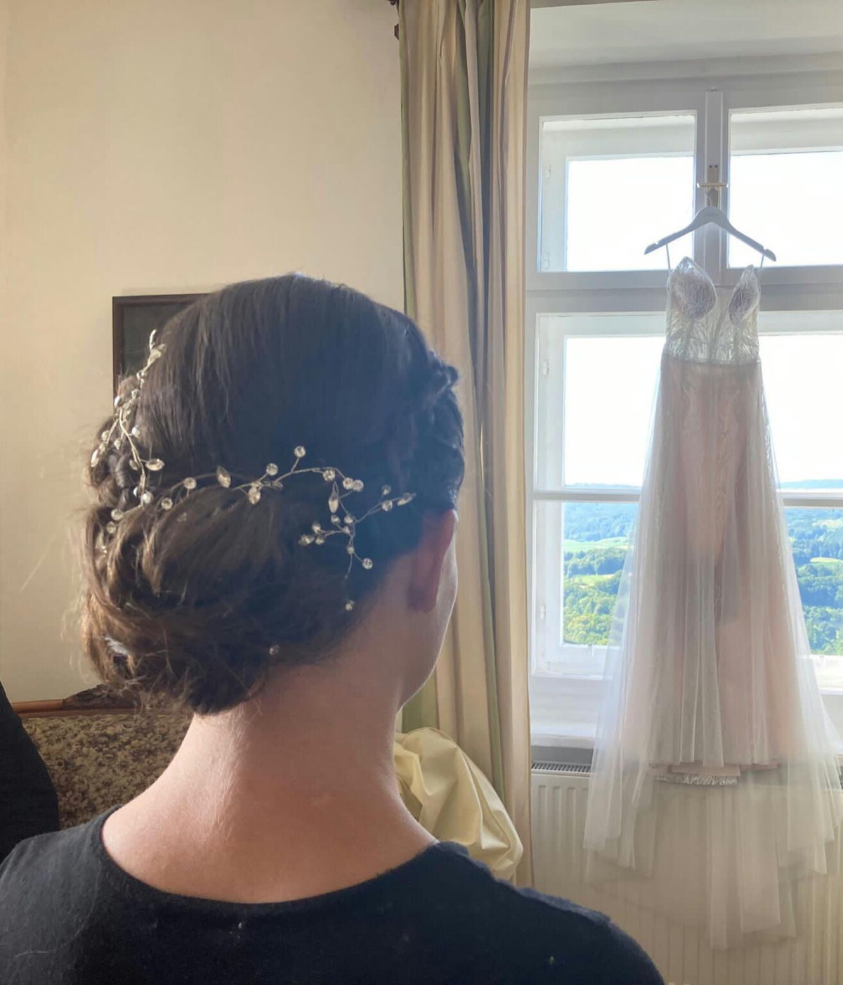 Brünette Braut mit elegantem Hochsteckfrisur-Dutt und Perlen-Haarranke vor Hochzeitskleid